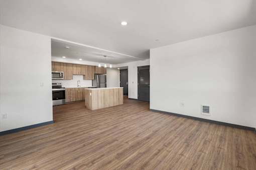 an empty living room and kitchen with wood floors and white walls at Elevation16 Apartments, Washington