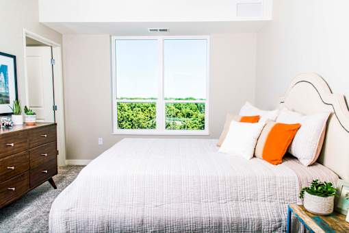 Inviting apartment bedroom with expansive nature views, featuring spacious walk-in closets and the comfort of central heating and air conditioning.