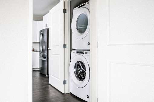 Compact stacked washer and dryer nestled in a hallway closet, providing convenient laundry facilities in a stylish apartment.