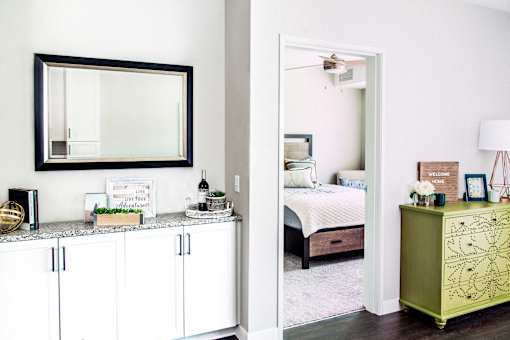 Spacious living room with built-in storage solutions, showcasing a seamless transition to the bedroom. The cozy bedroom, adorned with a soft carpet, invites comfort and relaxation.