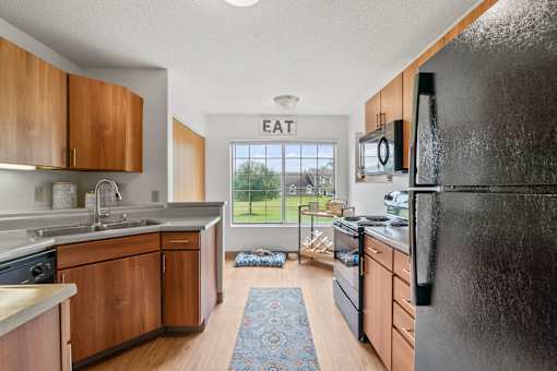 A kitchen with wooden cabinets and a black refrigerator.