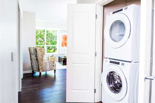 Compact stacked washer and dryer nestled in a hallway closet, providing convenient laundry facilities in a stylish apartment.