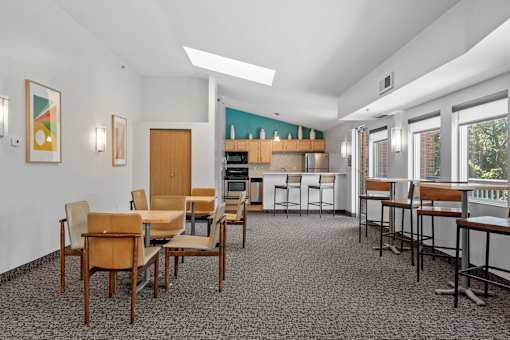 a dining room with tables and chairs and a kitchen in the background