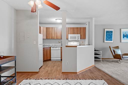 an open kitchen and living room with white appliances and wood flooring