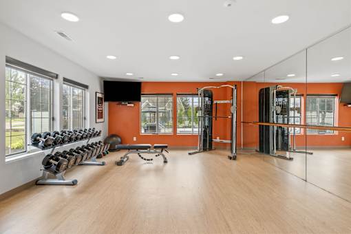 A gym with orange walls and wooden floors.