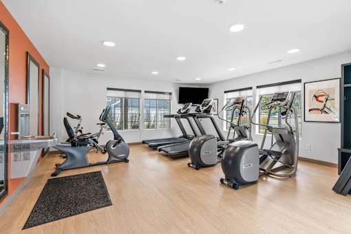 A gym with treadmills, exercise bikes, and a television.