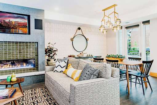 Cozy communal lounge in the apartment complex featuring stylish seating arrangements, a modern flat-screen TV, a warm fireplace, and a tabletop shuffleboard for residents to enjoy.