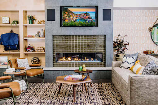 Cozy communal lounge in the apartment complex featuring stylish seating arrangements, a modern flat-screen TV, a warm fireplace, and a tabletop shuffleboard for residents to enjoy.