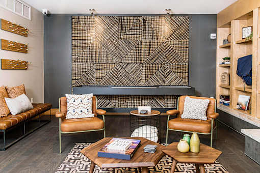 Cozy communal lounge in the apartment complex featuring stylish seating arrangements, a modern flat-screen TV, a warm fireplace, and a tabletop shuffleboard for residents to enjoy.