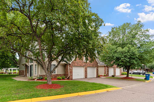 A tree in front of a house with a red mulch bed.