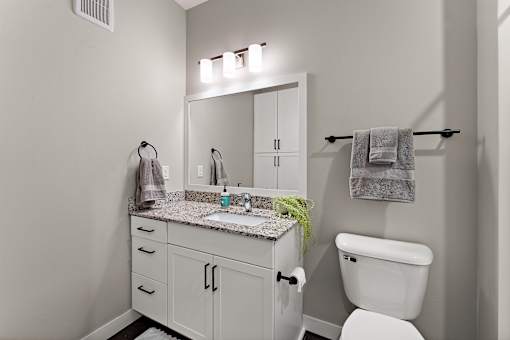 A bathroom with a white toilet and a white sink with a mirror above it.