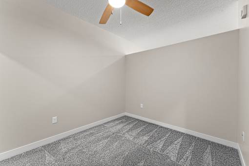 A room with a ceiling fan and a carpeted floor.