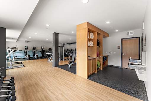 A gym with a variety of equipment including treadmills, weights, and exercise machines.