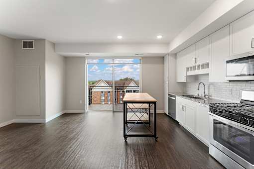 A kitchen with a table and a window overlooking a house.