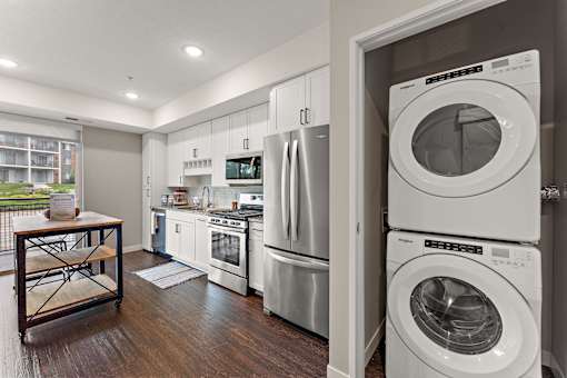 A modern kitchen with stainless steel appliances and a wooden table.