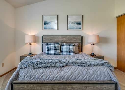 a bedroom with a bed and two lamps and a closet