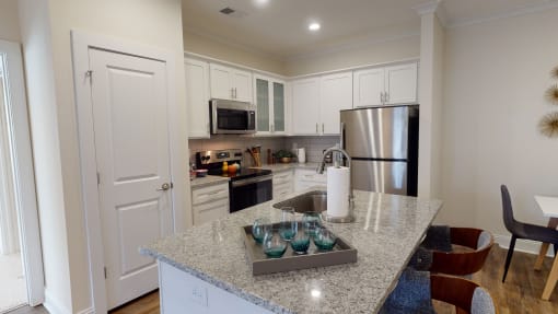 a kitchen with white cabinets and a granite counter top at The Retreat at Fuquay-Varina Apartments, Fuquay-Varina