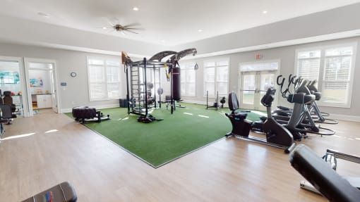 a home gym with a green rug and exercise equipment at The Retreat at Fuquay-Varina Apartments, Fuquay-Varina