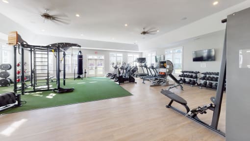 a spacious fitness room with a green rug and weights and cardio equipment  at The Retreat at Fuquay-Varina Apartments, Fuquay-Varina