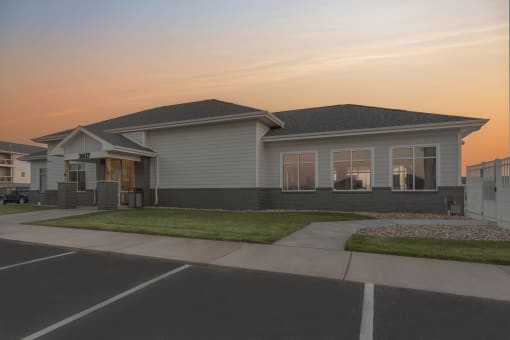 a house with a grassy yard and a sunset in the background