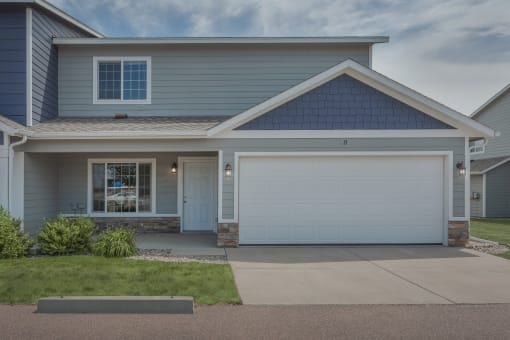 the front of a blue house with a white garage door