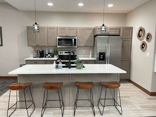 A modern kitchen with a white island and stools.