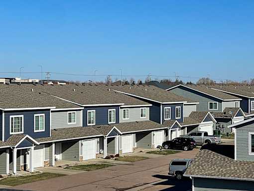 A row of houses with cars parked in front.
