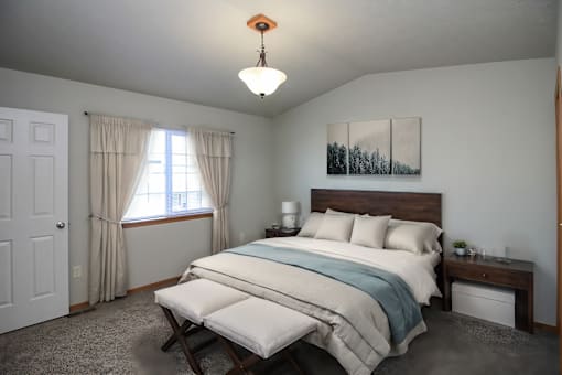 A bedroom with a bed, nightstand, and window.
