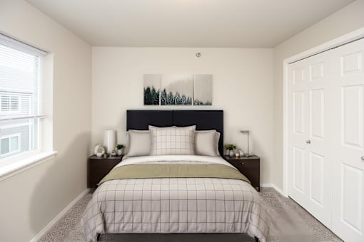 A bedroom with a bed, nightstands, and a window.