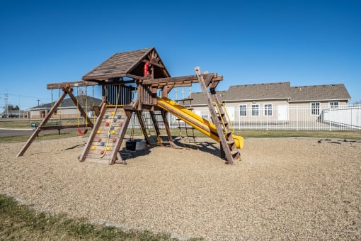 A wooden playground structure with a yellow slide.