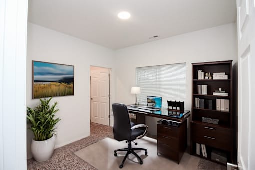 A room with a desk, chair, and bookshelf.