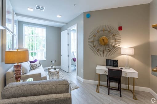 a living room with a desk and a mirror on the wall
