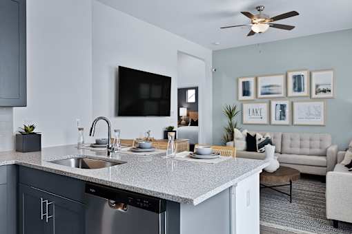 A modern kitchen with a grey countertop and a white sink.