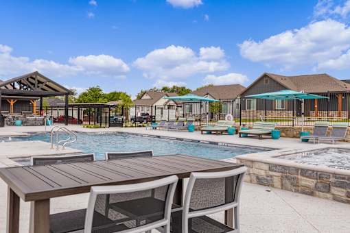 A poolside table and chairs are set up in front of a pool.