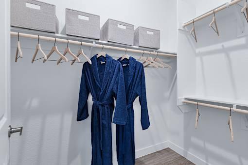 Two blue robes hanging on a rack in a room.