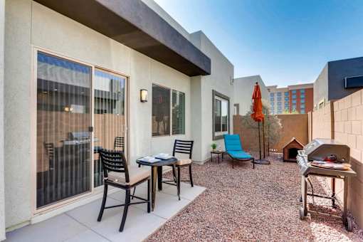 A patio with a table and chairs and a grill.