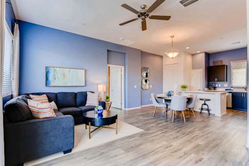 A living room with a blue couch and a ceiling fan.