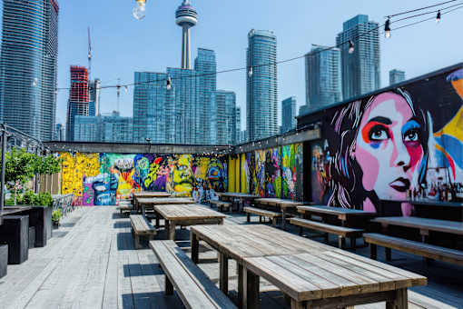 A mural of a woman's face is painted on a wall next to wooden benches.