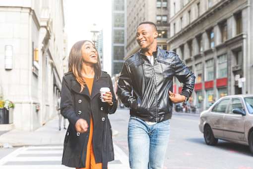 Two people crossing the street while holding hands.
