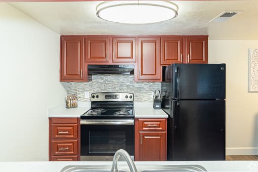 a kitchen with cherry cabinets and black appliances