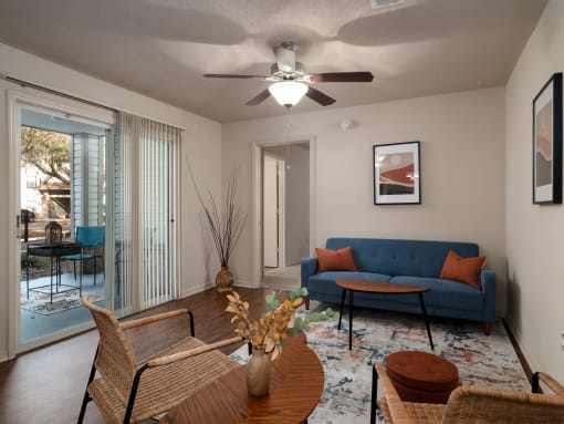 a living room with a blue couch and a ceiling fan at The Fountains Apartments, Pensacola, FL