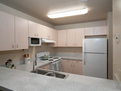 a kitchen with white cabinets and a sink and a refrigerator at The Fountains Apartments, Pensacola, 32514