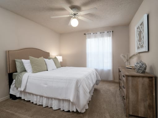 a bedroom with a large white bed and a ceiling fan at The Fountains Apartments, Pensacola, Florida, 32514