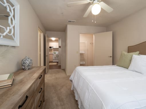 a bedroom with a large white bed and a ceiling fan at The Fountains Apartments, Pensacola, FL