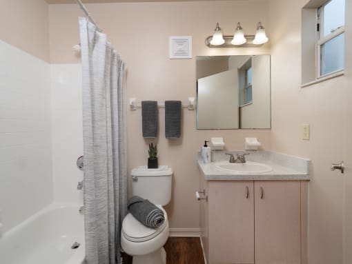 a bathroom with a shower toilet and sink and a mirror at The Fountains Apartments, Pensacola, 32514