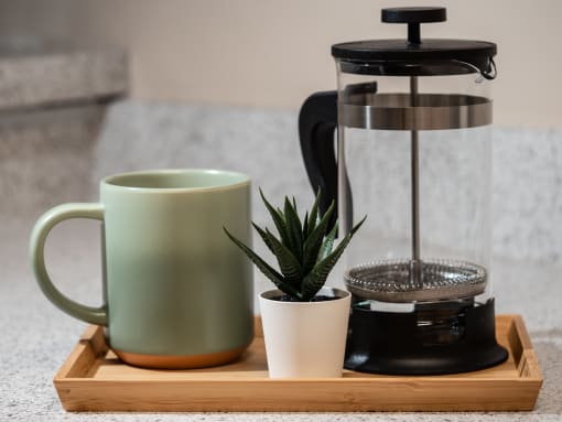 a coffee maker on a tray with a mug and a plant at The Fountains Apartments, Pensacola, Florida, 32514