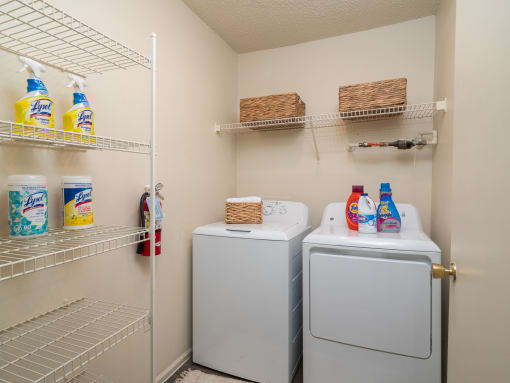 a laundry room with washer and dryer and a closet with shelves at The Fountains Apartments, Pensacola, FL