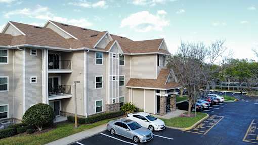 an apartment building with cars parked in a parking lot at Tivoli Apartments of Orlando, Oviedo