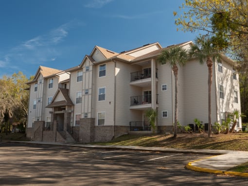 an apartment building on a street with palm trees at Stoneridge Apartments, Gainesville, FL