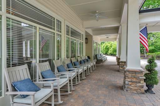 A porch with a row of chairs and an American flag.